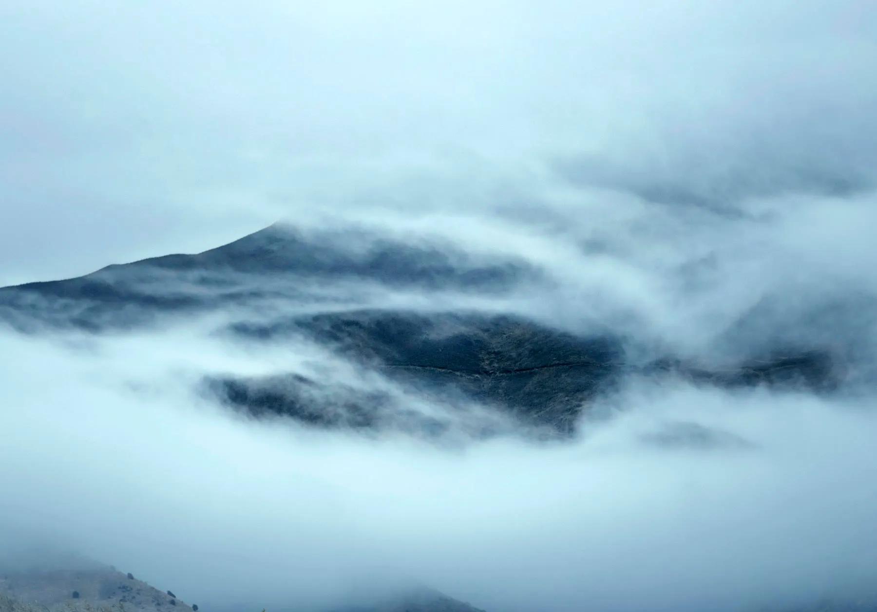 A mountain ridge breaking through a layer of cloud