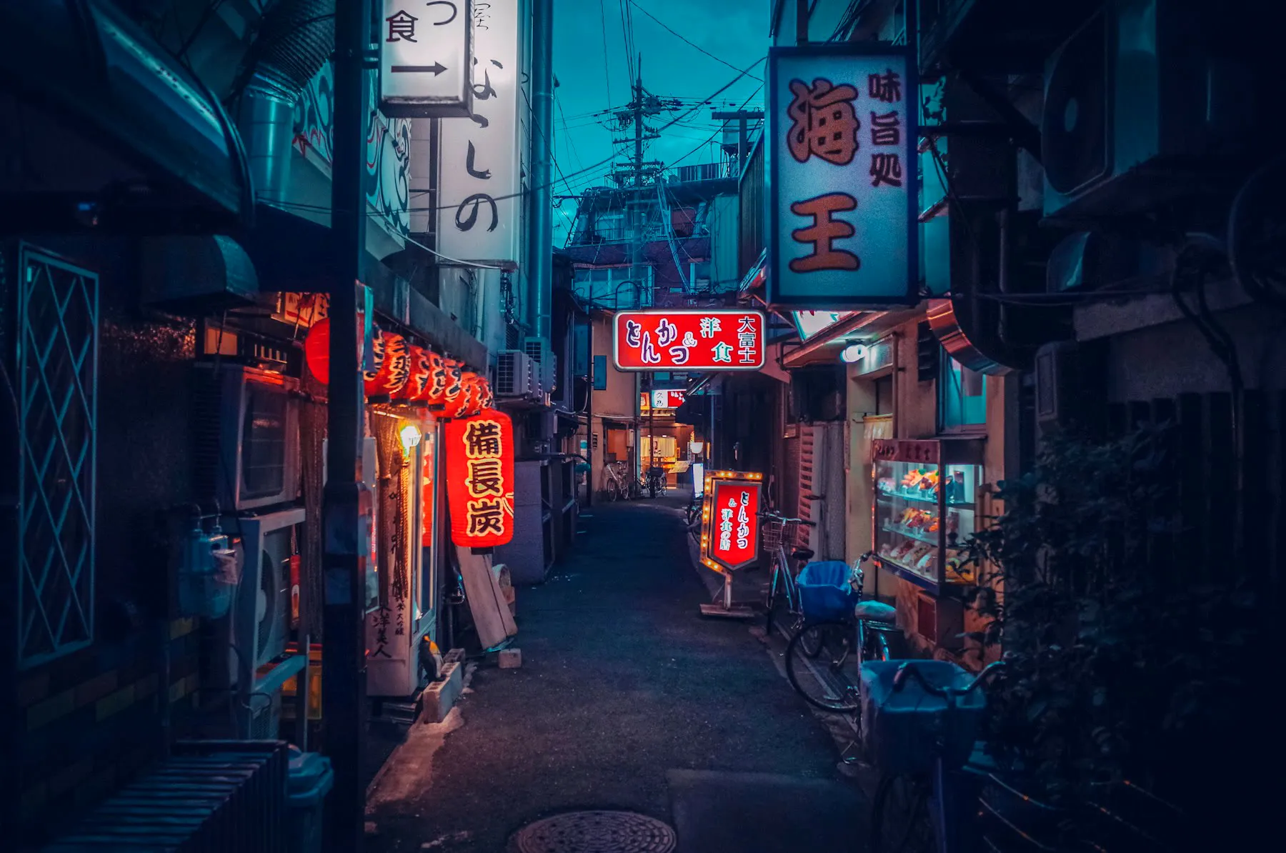 A narrow night alley lit by red and white shop signs