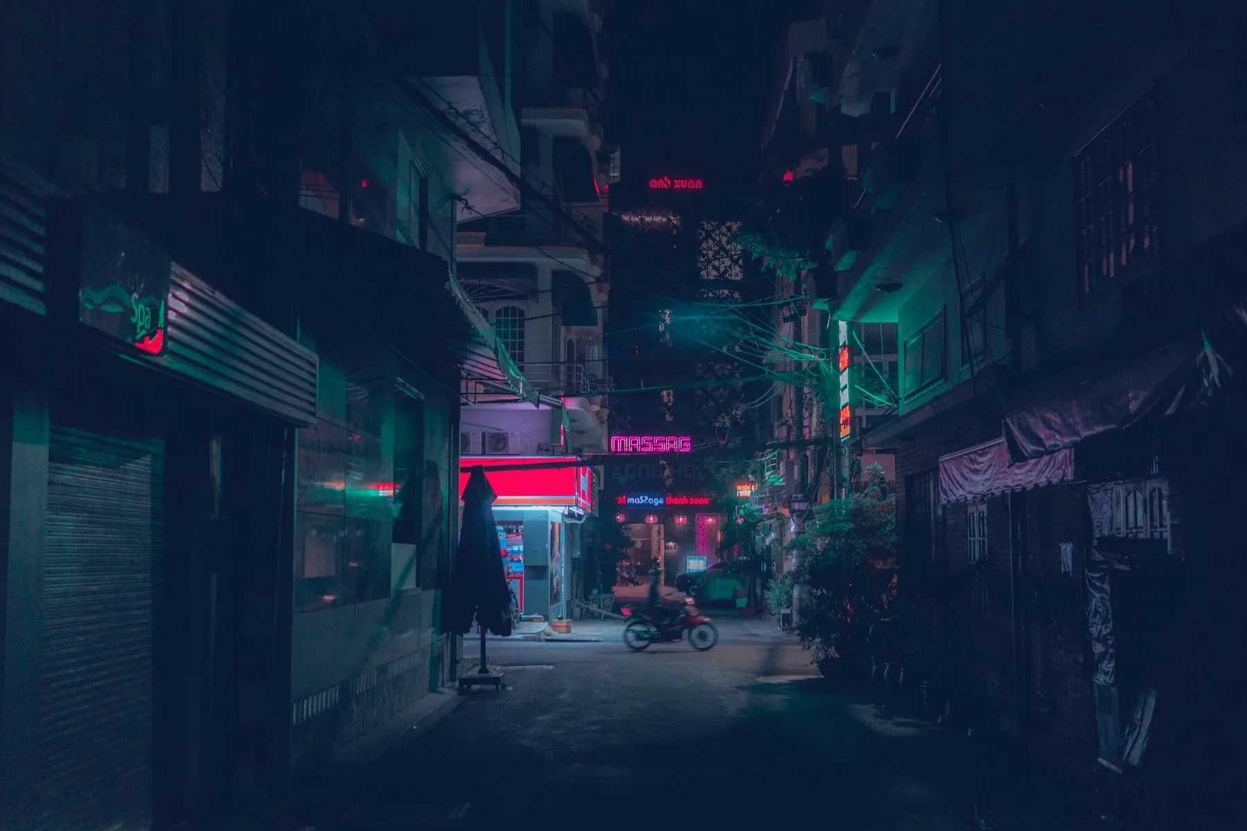 A motorcycle moving through a narrow city street at night